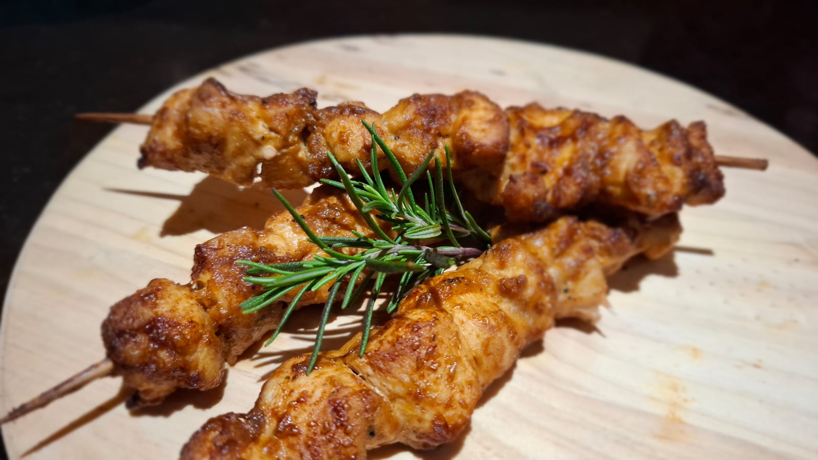 Grilled chicken sosaties with fresh rosemary on a wooden board