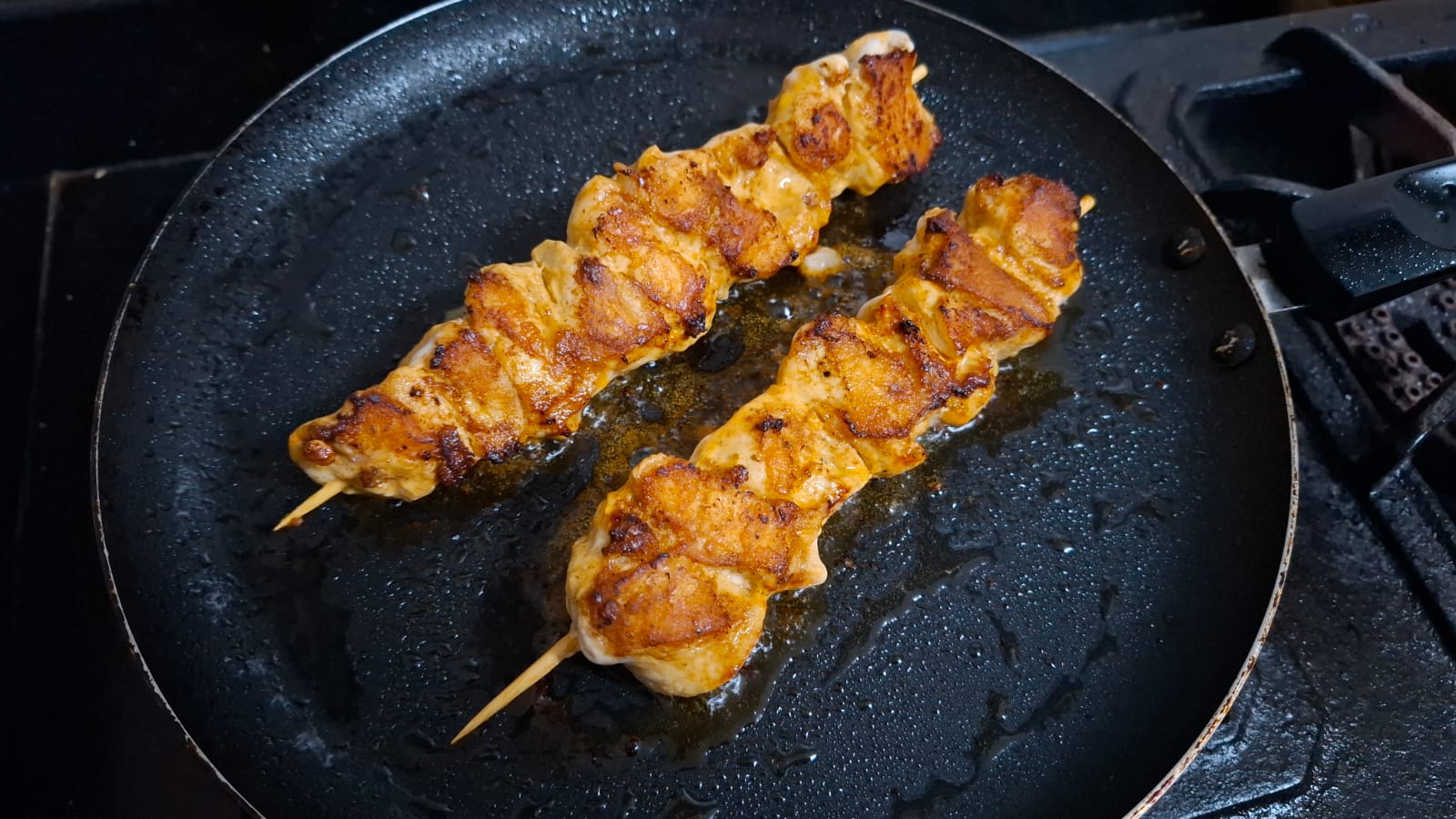 Golden brown chicken sosaties being pan-fried